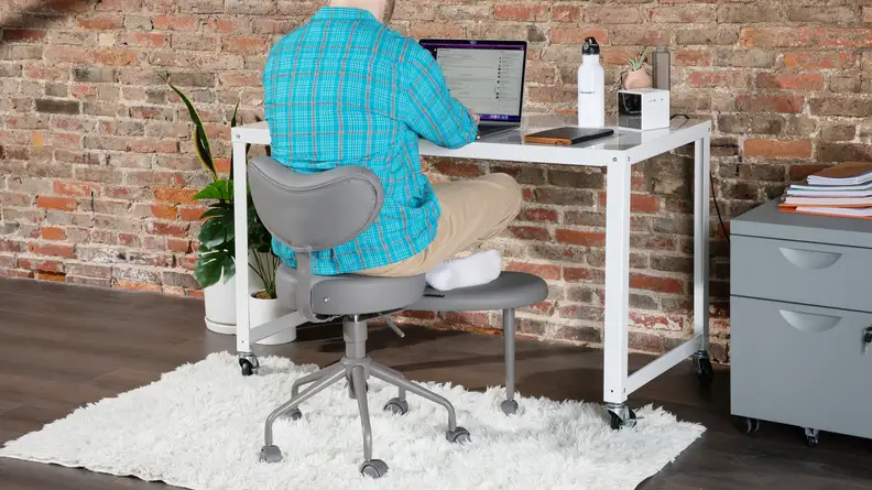 Person sitting cross-legged in the Pipersong Meditation Chair at desk while working on laptop.