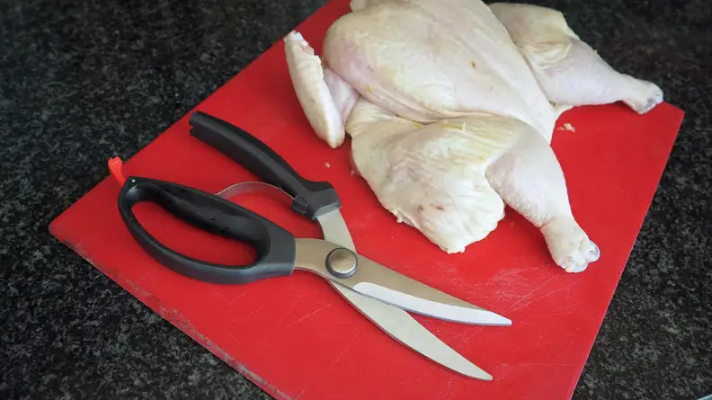 OXO Good Grips poultry shears set beside spatchcocked chicken on plastic cutting board