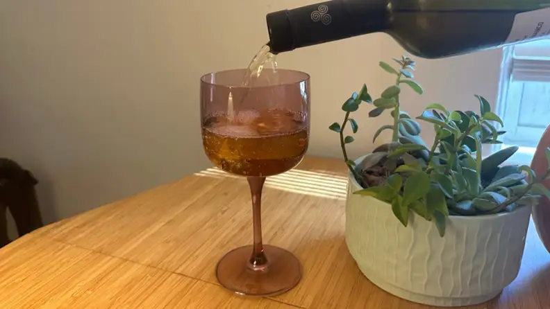 A purple wine glass being filled with wine.