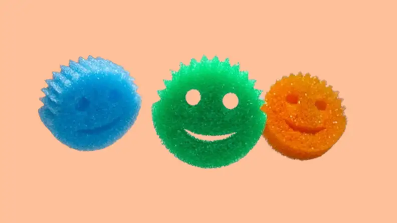 Three Scrub Daddy sponges on a tan background.