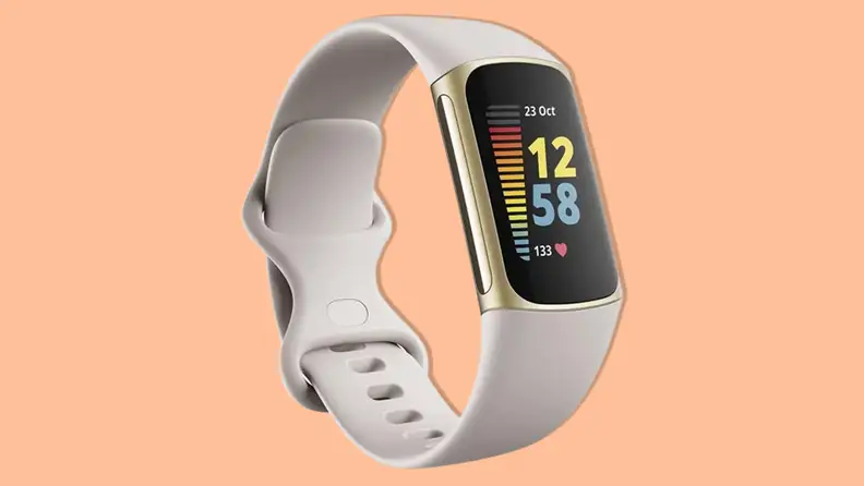 A Fitbit Charge 5 smartwatch with a tan silicone band on an orange background.