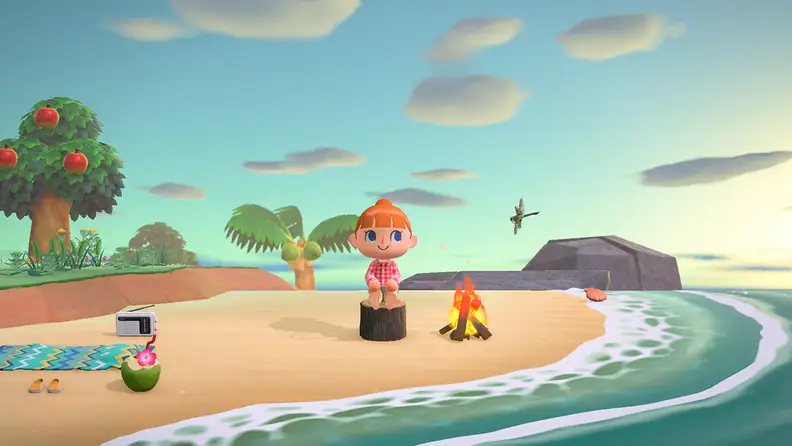A red-haired girl sits on a tree stump at the beach, looking out toward the waves with a smile.