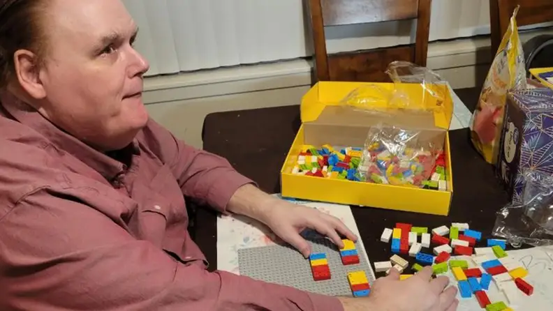 A man putting the Lego Braille Bricks together.