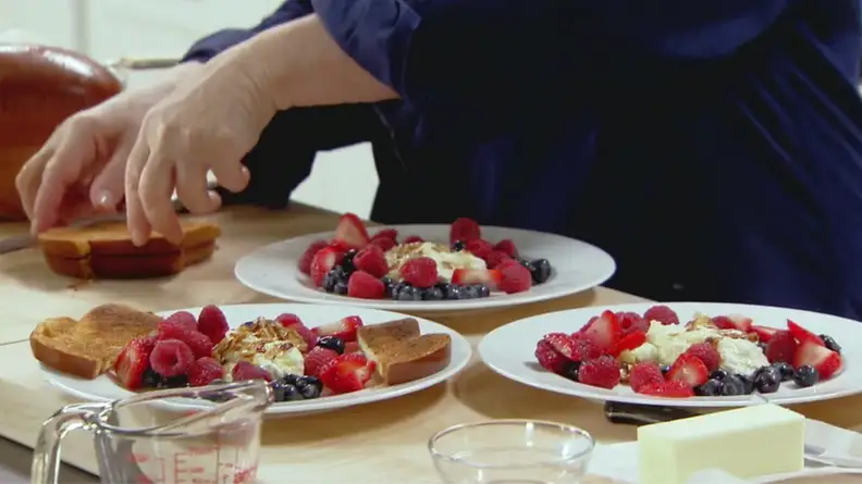 A still from Barefoot Contessa featuring Ina preparing plates of ricotta toast with berries.