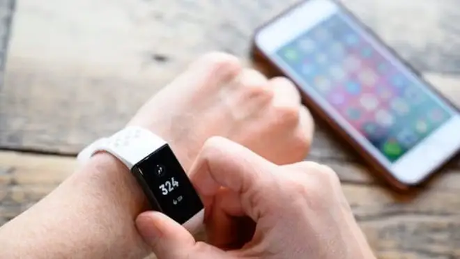Fitbit on wrist with iPhone in background