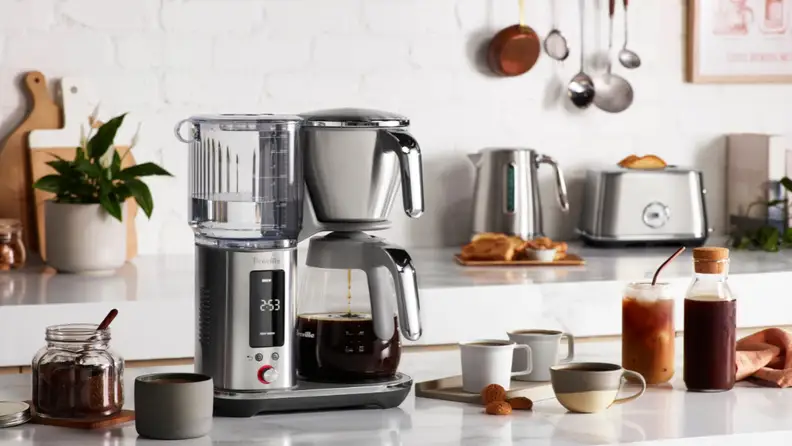 Breville drip coffee maker brewing into a glass carafe on a kitchen counter