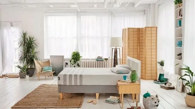 A mattress on a bed in a white room.