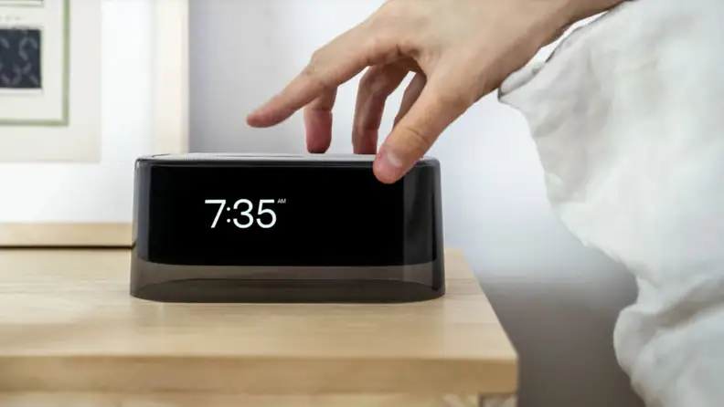 A hand reaches for the Loftie alarm clock, which says it's 7:35 a.m.