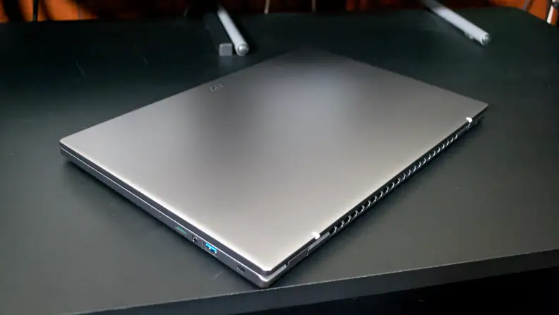 A closed, silver laptop on top of a black desk.