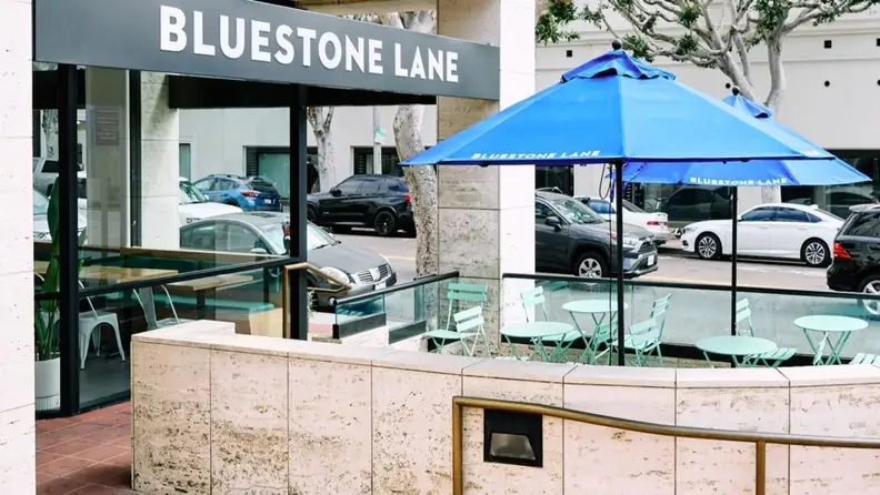 Cafe storefront with blue umbrellas and outdoor seating