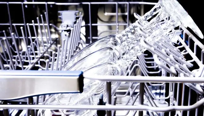 A close up shot of wine glasses stacked inside a dishwasher.