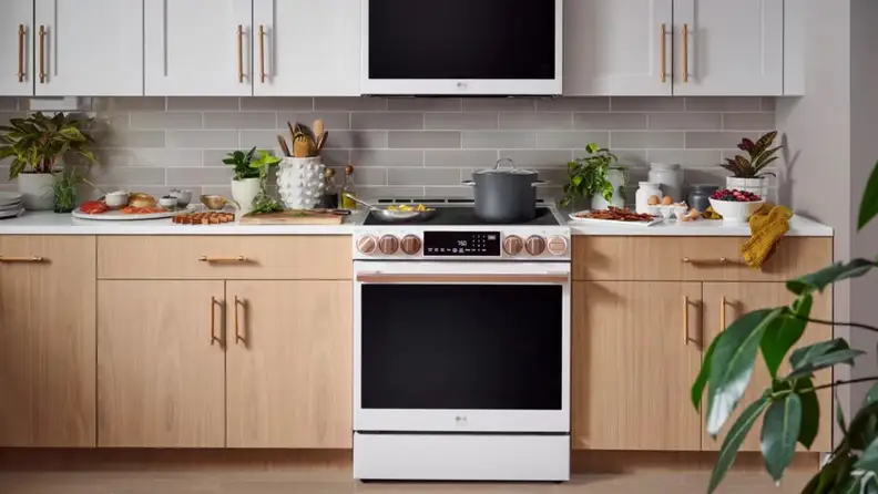 White slide-in induction range with rose-gold accents displayed in a modern kitchen surrounded by cooking ingredients and cookware.