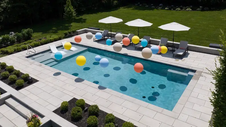 Aerial view of a backyard pool with colorful balls floating in the water