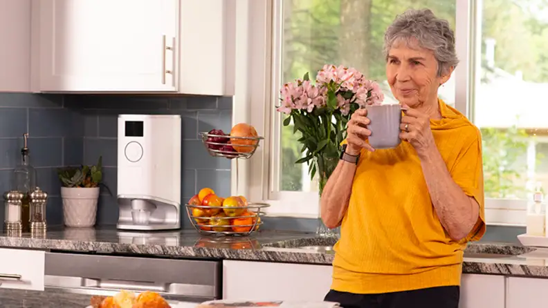 A person drinks coffee in their kitchen.