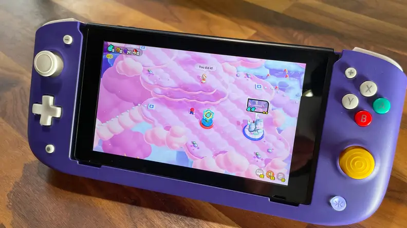 The CRKD Nitro Deck on a wood table with a game playing on the screen.