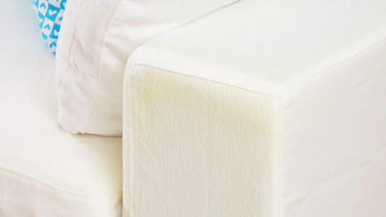 A close-up of the arm of the sofa with some yellow discoloration on the white fabric.