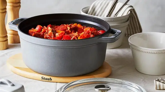 Gray cast iron cooking pot with food inside of top of counter.