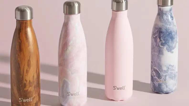Multi-colored reusable water bottles in front of pink background.