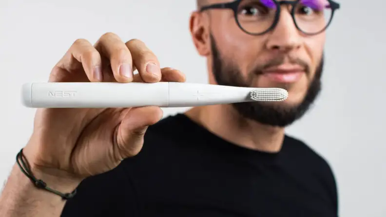 a person holding a nest toothbrush