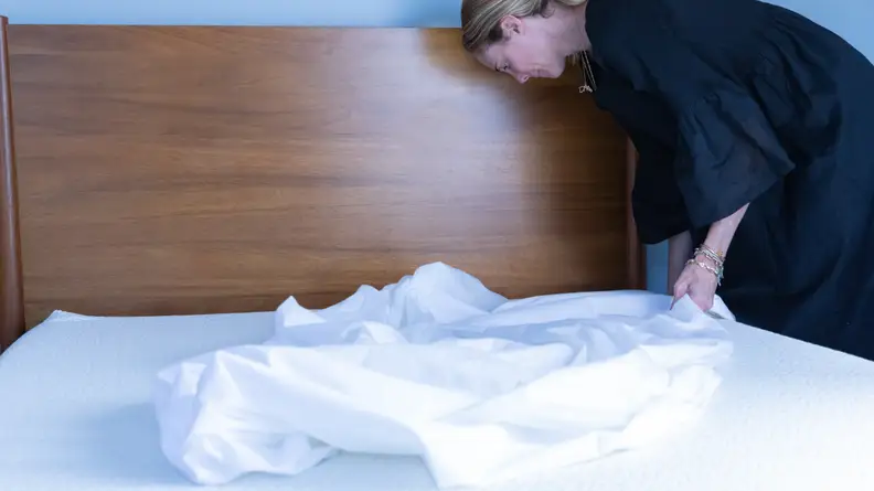 A woman putting a mattress cover on a 5 Little Monkeys mattress.