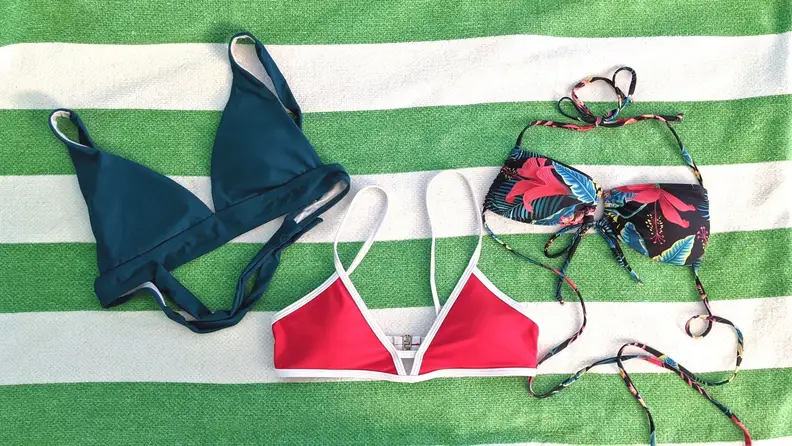 Three bikini tops lying flat on a beach towel