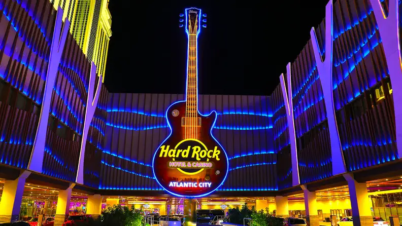 Hard Rock Hotel & Casino Atlantic City entrance with the iconic illuminated guitar sign glowing against the night sky.