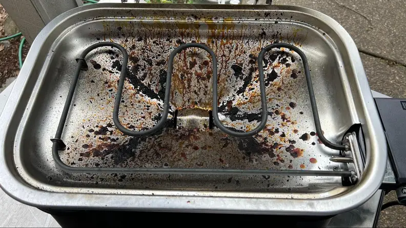 The inside of the Weber Lumin grill completely dirty.