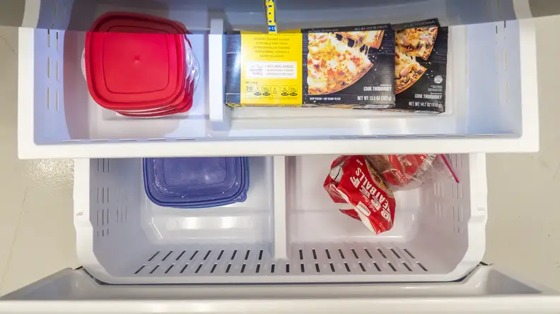 A top-down shot of the Samsung RF27T5201SG's freezer drawer, pulled out and stocked with items for scale.