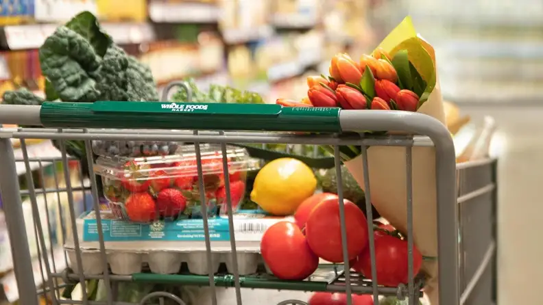 Close-up of a Whole Foods shopping cart filled with produce and flowers