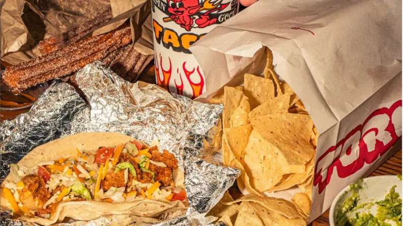 A taco on tin foil with chips and churros