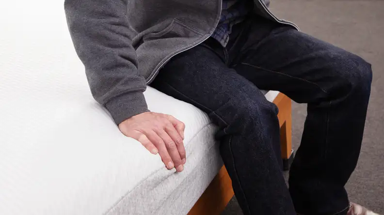 A person sitting on the edge of the Tuft & Needle Original mattress