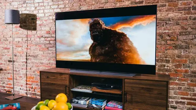 Smart TV in front of brick wall on top of wooden console.