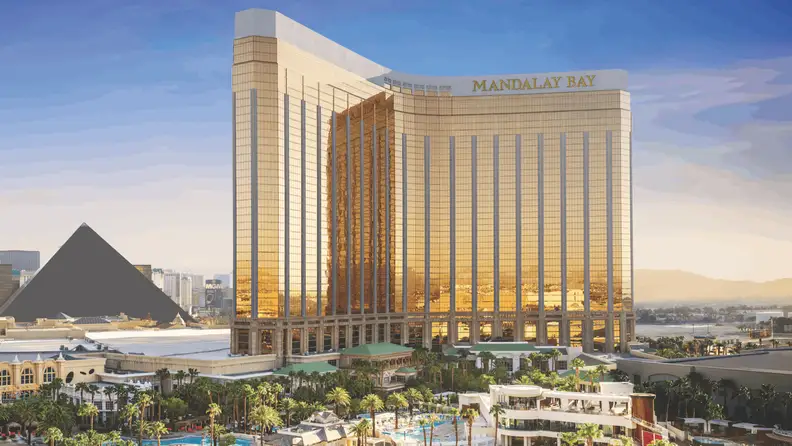 Mandalay Bay’s gold-tinted hotel tower reflecting sunlight above the resort grounds, pools, and surrounding Las Vegas skyline.