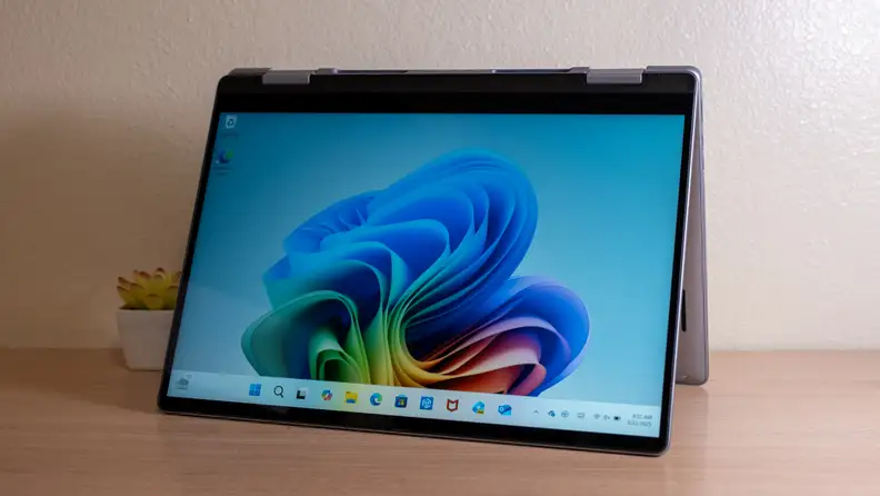 An open silver laptop sits on a brown desk