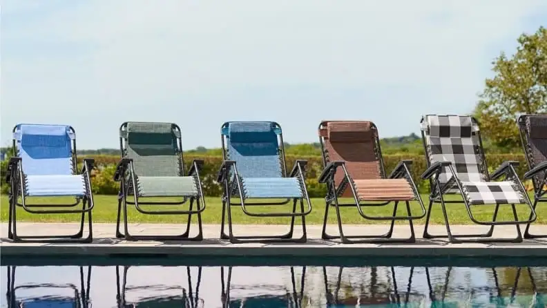 Five patio chairs sitting alongside a pool.