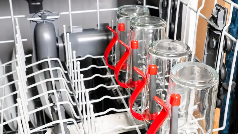 A close-up of the GE GDF630PSMSS dishwasher's upper rack, which shows off its bright red bottle jets. Glasses and dishes are loaded in for scale.
