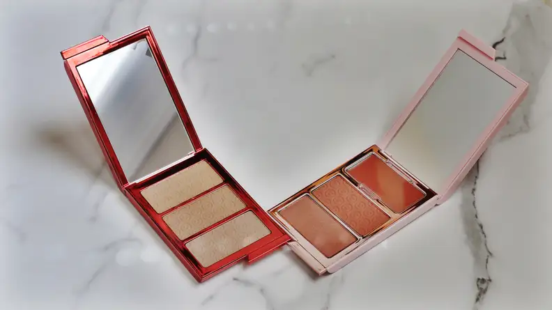 Two open palettes, one a bronze color and the other a light pink color, sit side by side.