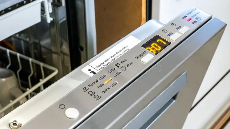 The Miele dishwasher’s door is open slightly, showing its top control panel.