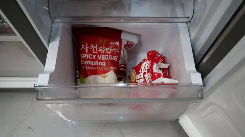 A close-up of one of the Whirlpool WRQA59CNKZ's freezer drawers. In it are two bags of dumplings.