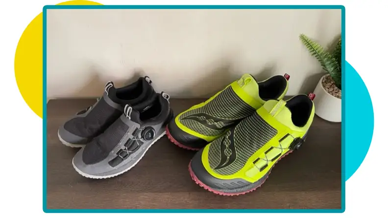 Gray and black The Big Kid’s Switchback 2.0 sneaker next to the multi-color Saucony Switchback 2 shoe indoors on wooden shelf.