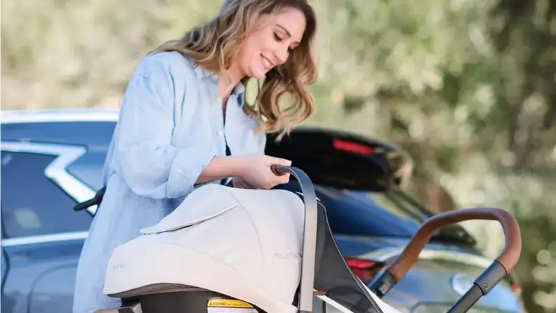A woman setting up the car seat on a stroller.