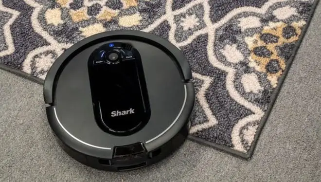 A dark gray Shark vacuum going over a carpet