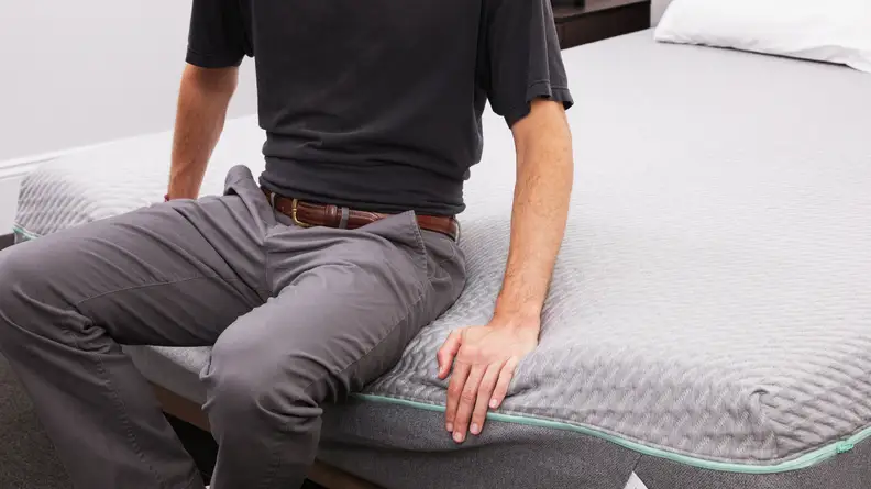 A person sitting on the edge of the mattress.