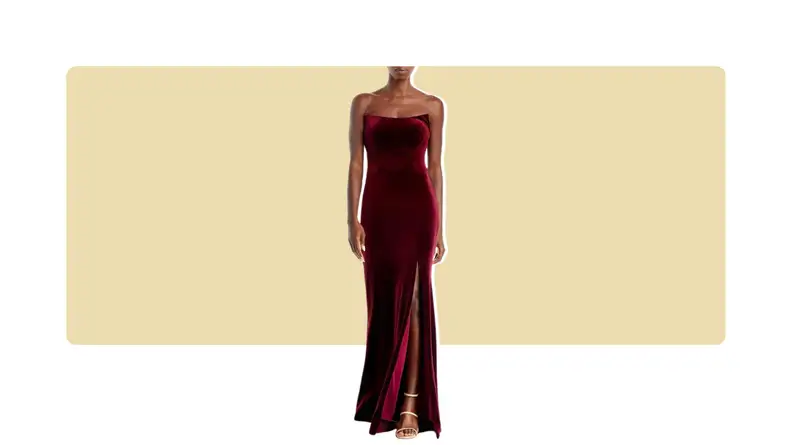 A model wearing a dark red velvet strapless gown with a leg slit.