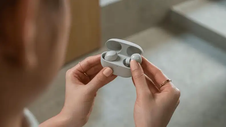 Person holding Sony WF-1000XM6 earbuds in their charging case.