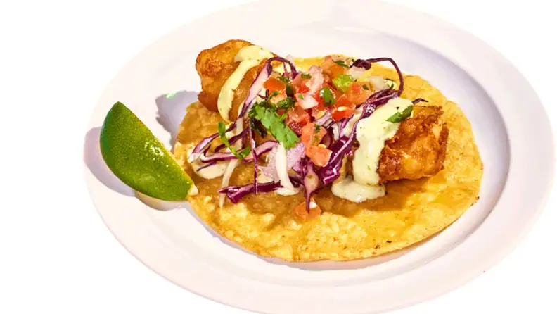 A crispy fish taco topped with cabbage slaw and pico de gallo