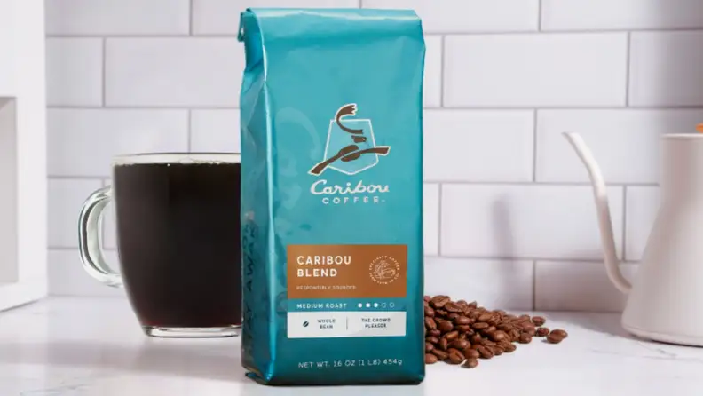 Coffee bag standing beside a mug and scattered beans
