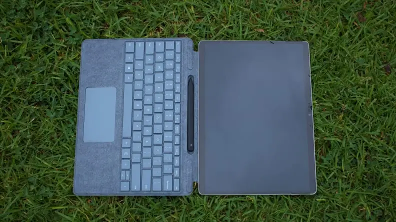 The Surface Pro X laid atop grass with the Surface Keyboard attached.