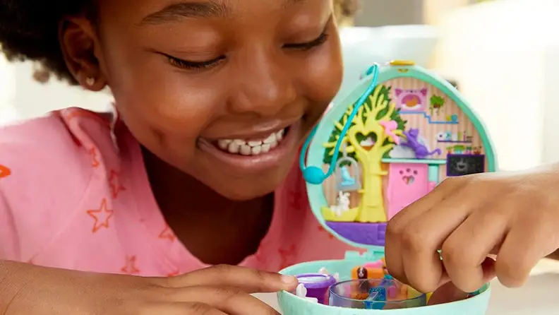 Young child playing with small Polly Pocket toy.