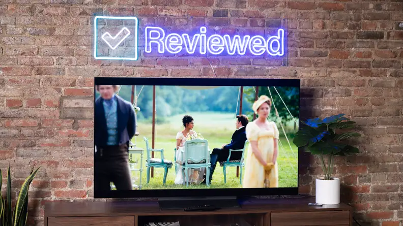 LG C2 in front of brick wall next to potted plants with movie playing on screen.